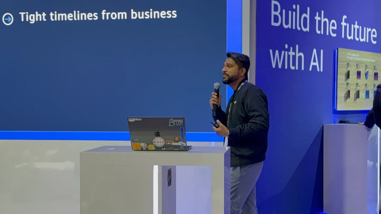 Ganesh Raam at the lectern beside a slide reading Tight timelines from business